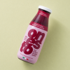 Fles granaatappel aardbei framboos sap op een lichtgele achtergrond