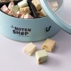 Lichtblauw bewaarblik met gemengde nougat en enkele stukjes naast het blik