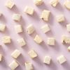 Losse blokjes soft nougat vanille verspreid over een lichtroze achtergrond