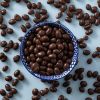 Kom gevuld met biologische melkchocolade pinda's, omringd door losse chocolade pinda's.