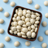 Witte chocolade kruidnoten in een vierkant schaaltje op lichtblauwe achtergrond