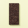 Pure chocoladereep met cacaonibs op een lichtgele achtergrond
