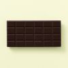 Achterkant van pure chocoladereep met chocoladeblokjes op een lichtgele achtergrond
