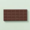 Achterkant van melkchocoladereep met chocoladeblokjes op een lichtgroene achtergrond