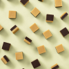 Losse blokjes fudge vanille & choco verspreid over een lichtgele achtergrond