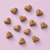 Negen chocolade hartjes karamel verspreid op een lichtroze achtergrond
