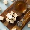 Roomnougat met amandelen geserveerd op een houten plank met thee en een theezeefje