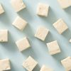 Losse blokjes roomnougat verspreid over een lichtblauwe achtergrond