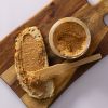 Brood met pindakaas en stukjes pinda met een open pot op een houten plank
