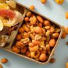 Pittige borrelmix met pinda’s en snacks in een houten bakje