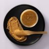 Brood met cashewpasta en een open pot op een zwarte schaal