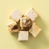 Blokjes soft nougat met kaneelamandelen op een lichtgele achtergrond