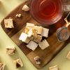 Soft nougat met kaneelamandelen op een houten serveerplank naast een glas thee