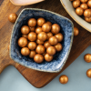 Crunchy choco’s goud in blauw schaaltje op houten plank