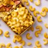 Spicy cashew bites in snackmix op lichtpaarse achtergrond