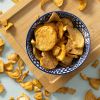 Appel-kaneelchips in een decoratief schaaltje op een houten plank