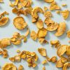 Losse appel-kaneelchips verspreid over een lichtblauwe achtergrond