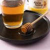 Acaciahoning met honinglepel en glas thee op een zwart dienblad
