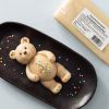Marsepein teddybeer op een zwarte schaal met verpakte amandelmarsepein