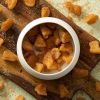 Appel kaneel chunks in een wit schaaltje op een houten plank