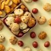 Kingbollen mix in een houten schaaltje met verschillende krokante snacks en rode crackers eromheen