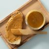 Brood met pindakaas met een open pot op een houten plank