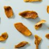 Losse stukken ongezoete gedroogde mango op een lichtblauwe achtergrond