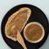 Brood met romige amandelpasta en een open pot op een zwarte schaal