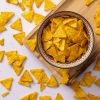 Mini tortilla chips in een schaaltje op een houten plank
