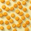 Baked round chili crackers los verspreid over een lichtgele achtergrond