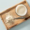 Rijst-eiwitpoeder met een glas eiwitshake op een houten plank