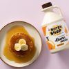 Bovenaanzicht van pannenkoeken met banaan en een fles ahornsiroop