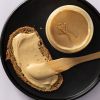 Brood met romige bueno pasta en een open pot op een zwarte schaal