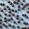 Chocolade macadamia noten verspreid over een lichtblauwe achtergrond