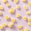 Losse ananas bites verspreid over een lichtpaarse achtergrond