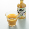 Glas met gembersap en fles biologisch gembersap 500 ml op de achtergrond