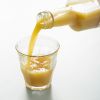Biologisch gembersap dat vanuit de fles in een glas wordt geschonken