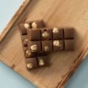 Twee repen melkchocolade met hazelnoten op een houten plank, schuin van boven gefotografeerd