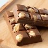 Close-up van repen melkchocolade met zichtbare hazelnoten op een houten plank