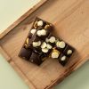 Pure chocolade choc block Sweet ’n Salty met pretzelstukjes en witte chocoladedrops op houten plank