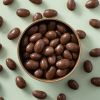 Melkchocolade amandelen in een rond schaaltje met groene achtergrond