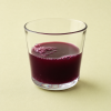Glas met granaatappel aardbei framboos sap op een lichtgele achtergrond