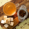 Kop limoncello spritz fruitthee met theezeef en blokjes nougat op een houten plank