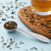 Royal Tea doseerlepel gevuld met thee en glas thee