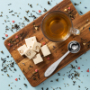 Royal Tea doseerlepel met kop thee en nougat op houten plank