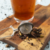 Thee-ei tang met losse thee en glas thee op houten plank