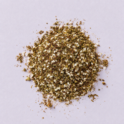 Hoopje Za'atar kruidenmix met sesamzaad op een lichtpaarse achtergrond