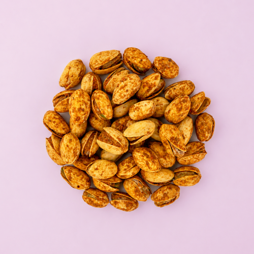 Geroosterde pistachenoten op een lichtroze achtergrond Geroosterde pistachenoten op een lichtroze achtergrond