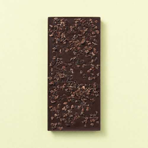 Pure chocoladereep met cacaonibs op een lichtgele achtergrond Pure chocoladereep met cacaonibs op een lichtgele achtergrond