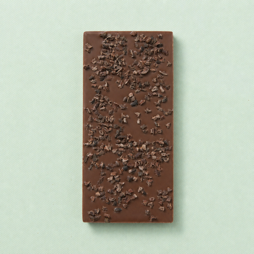 Melkchocoladereep met cacaonibs op een lichtgroene achtergrond